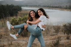 two women in jeans and white shirts are holding each other while they smile at the camera