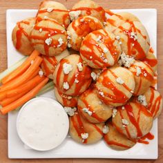 a white plate topped with rolls covered in cheese and carrots next to dipping sauce