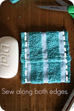 a wooden table topped with a blue towel next to a white soap bar and scissors