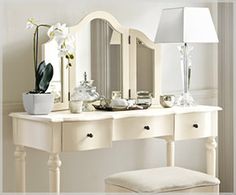 a white dressing table with mirror and stool