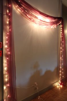 a curtain with lights hanging from it's side in front of a white wall