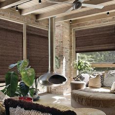 a living room filled with lots of furniture and windows covered in bamboo blind shades on top of them