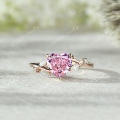 a pink heart shaped diamond ring with leaves on it