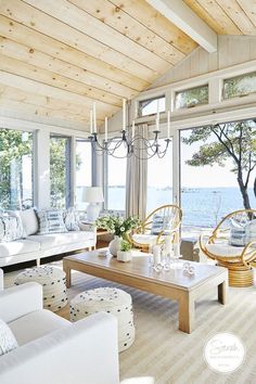 a living room filled with lots of furniture and large windows overlooking the water's edge