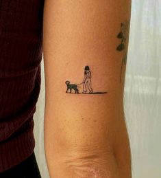 a woman with a small tattoo on her arm holding a dog and walking it's owner