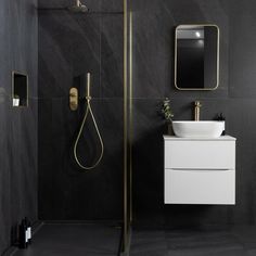 a black and white bathroom with gold accents on the shower head, sink, and mirror