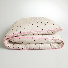 two pillows on top of each other with black and pink trimmings in the middle