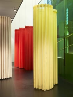 four different colored vases sitting next to each other in front of a glass wall