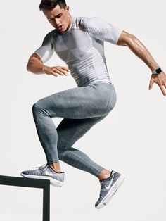 a man in grey and white is jumping over a rail with his hands on his hips