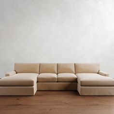 a beige couch sitting on top of a hard wood floor next to a white wall