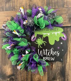 the witches brew halloween wreath is hanging on a wooden door with green and purple decorations