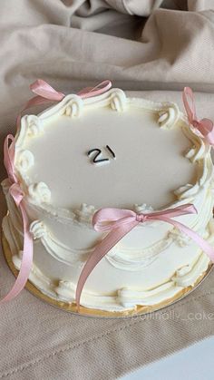 a white cake with pink ribbon and the number 25 on it