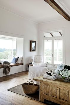 a living room filled with furniture and windows next to a wooden table topped with flowers