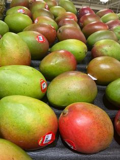 many different types of fruit on display in a market stall, including mangoes and pomegranates