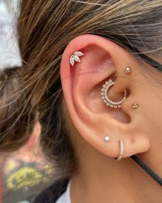 a woman wearing three different types of ear piercings