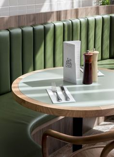 a table with a book, fork and knife on it in front of a green booth