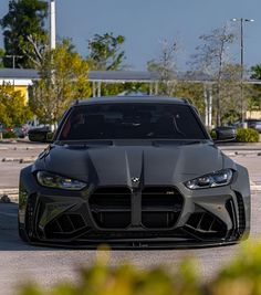 the front end of a gray sports car parked in a parking lot with other cars behind it