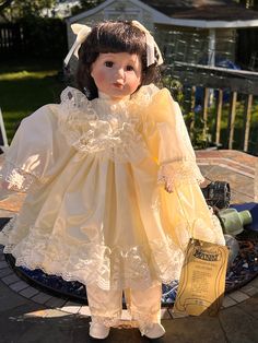 a doll is dressed in yellow and holding a book on a patio table with a blue fire hydrant behind it