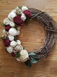 a wreath with white and red flowers on top of a wooden floor in the shape of a heart