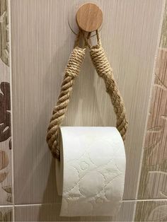 a rope wrapped toilet paper holder hangs on the wall