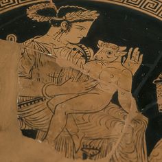 an ancient greek vase with a woman holding a child on it's lap, painted in gold and black