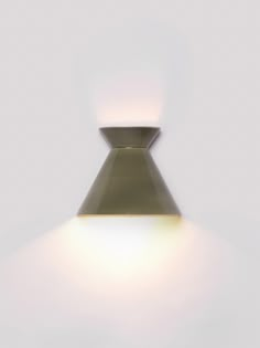 a light that is on in the middle of a white wall with a small lamp below it