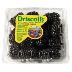 a plastic container filled with blackberries on top of a white surface