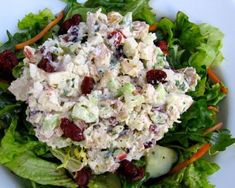 a salad with chicken and cranberries is on a white plate