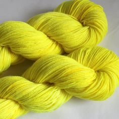 three skeins of yellow yarn on a white surface