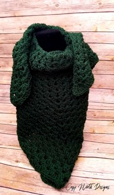 a green crocheted scarf sitting on top of a wooden floor