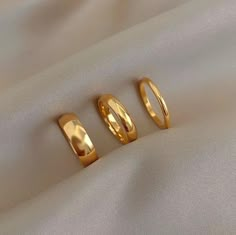 three gold rings sitting on top of a white cloth