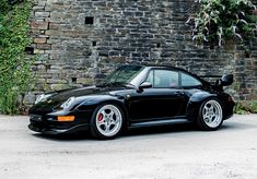 a black sports car parked in front of a brick wall