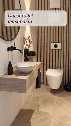 a white toilet sitting next to a sink in a bathroom under a round mirror with the words guest toilet washbasin above it