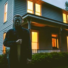 a scary looking man standing in front of a house