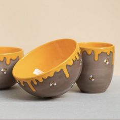 three yellow and gray bowls with dripping paint on them