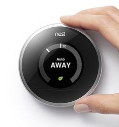 a person's hand is holding an nest thermostat on a white surface