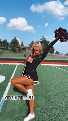 the cheerleader is posing on the field with her pom - poms in hand