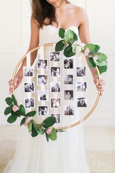 a woman is holding a wreath with photos on it and greenery around the frame