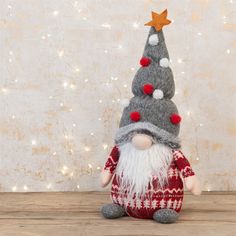 a small gnome with a red and white sweater is sitting in front of a christmas tree