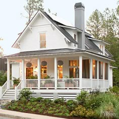 a white house with porches and balconies on the front, surrounded by greenery