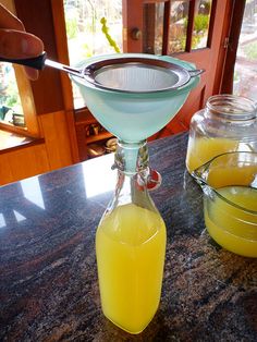 a glass filled with liquid sitting on top of a counter next to two jars full of orange juice