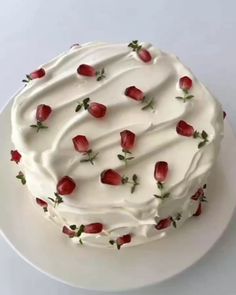 a cake with white frosting and red strawberries on the top is sitting on a plate