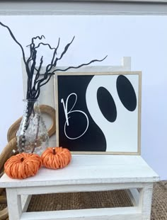 a white table topped with two pumpkins and a framed halloween sign next to it