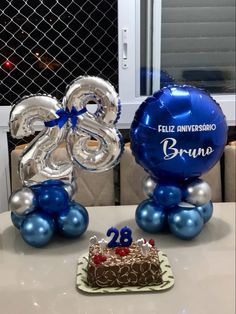 two balloons and a cake on a table with the number 28 in front of it