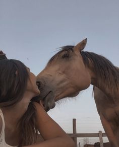 a woman kissing the nose of a horse