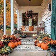 the front porch is decorated with pumpkins and flowers