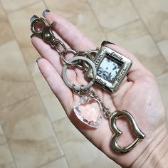 a person is holding two key chains and a small square shaped watch on their palm