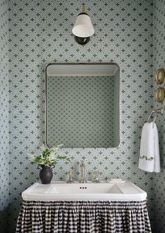 a white sink sitting under a bathroom mirror next to a black and white checkered table cloth