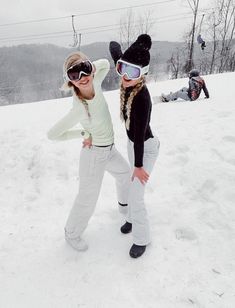 two people standing in the snow wearing ski goggles