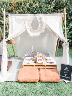 a white canopy bed sitting on top of a lush green field